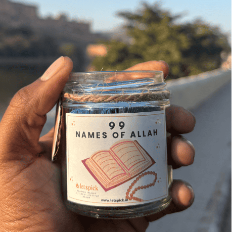 Hand holding a candle jar labeled '99 Names of Allah' with a blurred outdoor background.